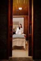 Una habitación con una cama, techo de madera y una mesita con un jarrón.