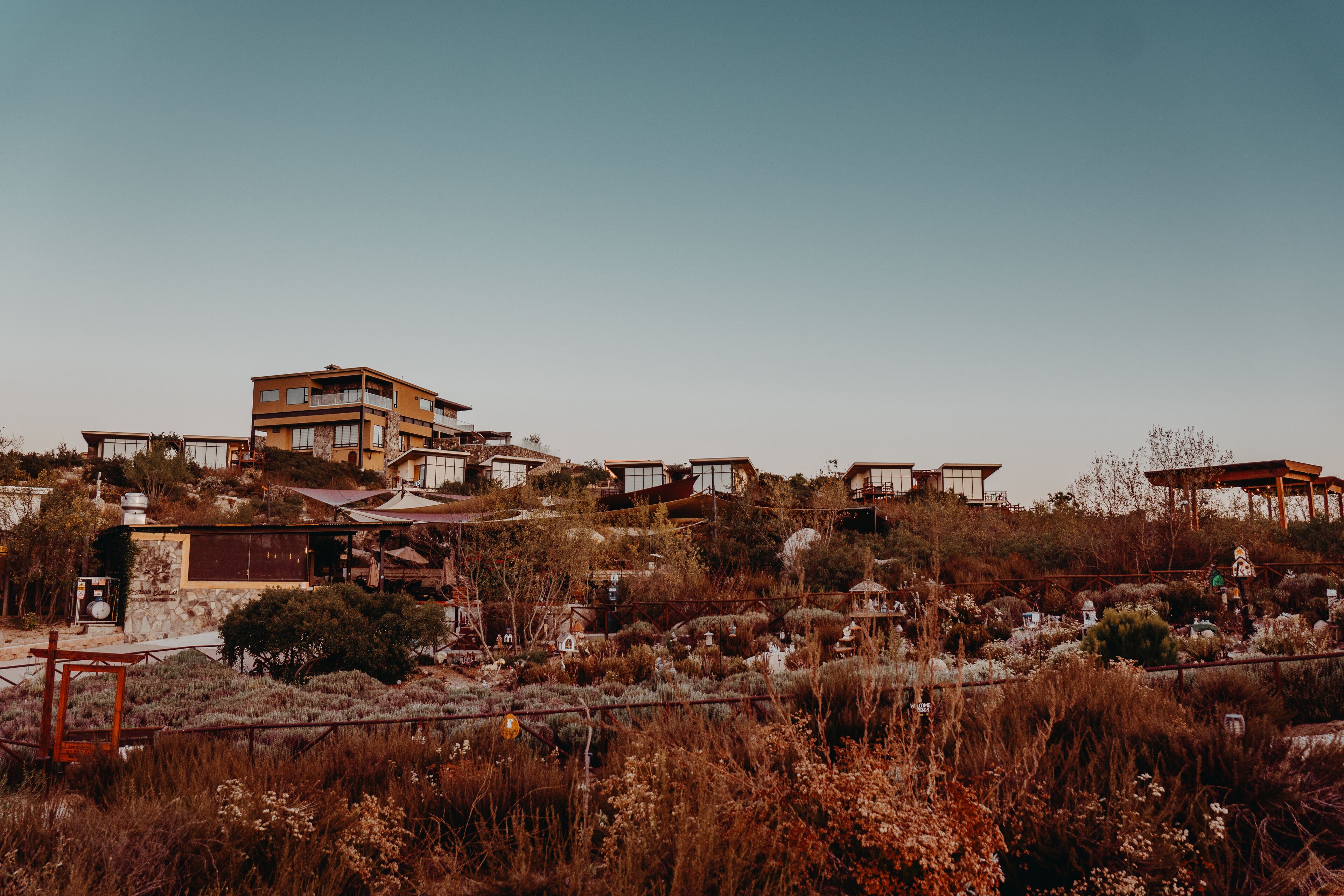 Una zona residencial en una ladera con varias casas, incluyendo una casa de dos pisos destacada con un balcón.