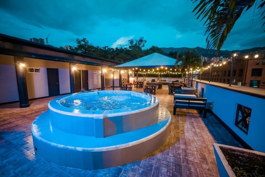 Un jacuzzi rond entouré d’un patio, avec des sièges d’extérieur et des guirlandes lumineuses.