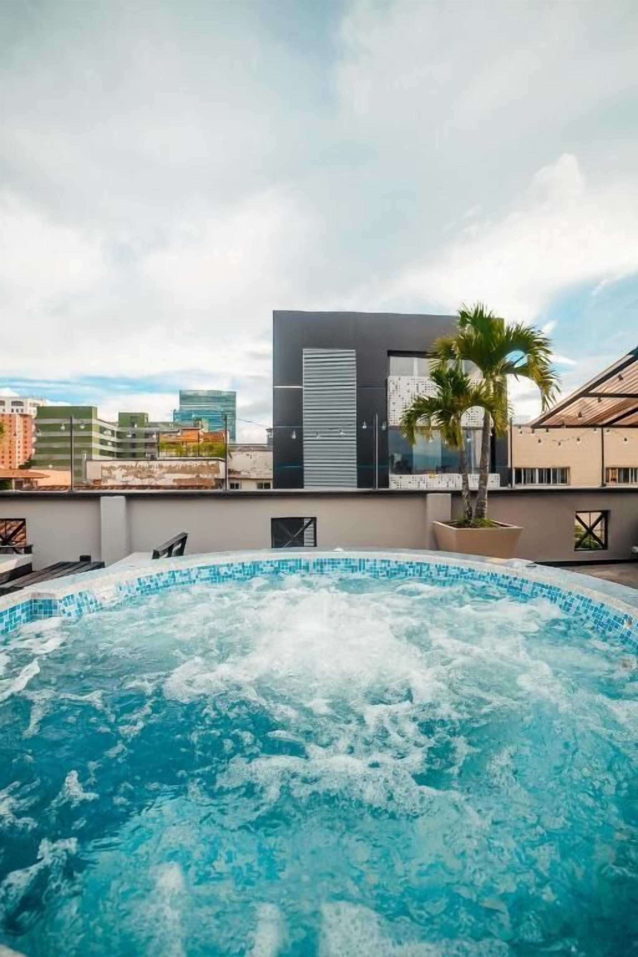 A rooftop swimming pool with a view of a modern building and palm trees.