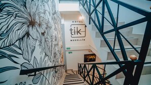 A staircase with a geometric railing design leading to a hotel sign labeled "HOTEL tK MEDELLIN". - Tik by Bernalo Hotels (Medellín)