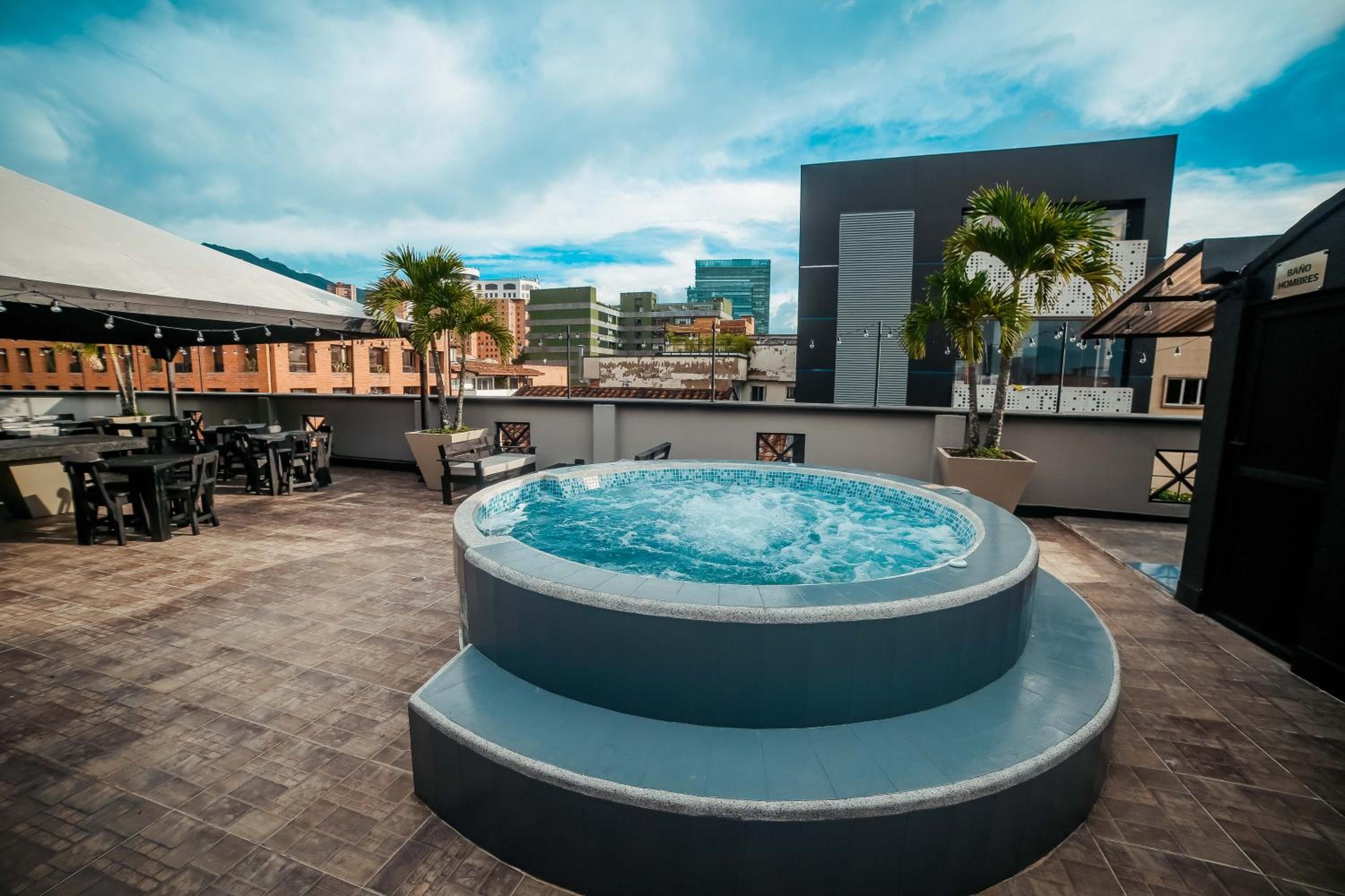 A rooftop terrace with a hot tub, outdoor seating, and a city view.