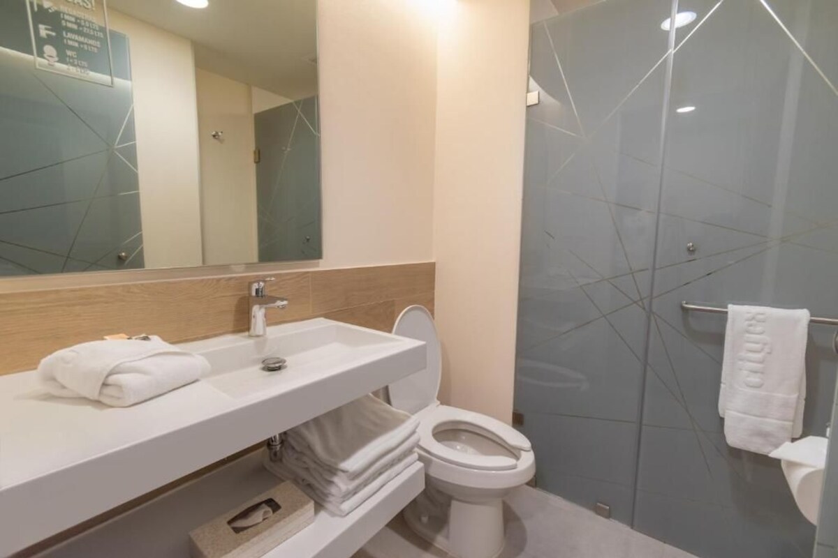 A modern bathroom with a white sink, mirror, and toilet.