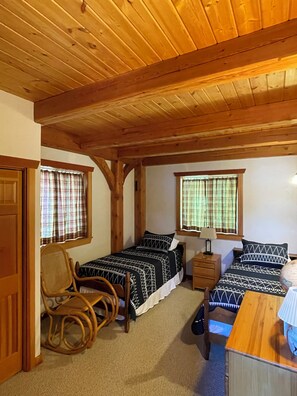 A room with two beds, a wooden ceiling, a rocking chair, and a small table with a lamp. - —Priest Lake Waterfront Escape— (Coolin)