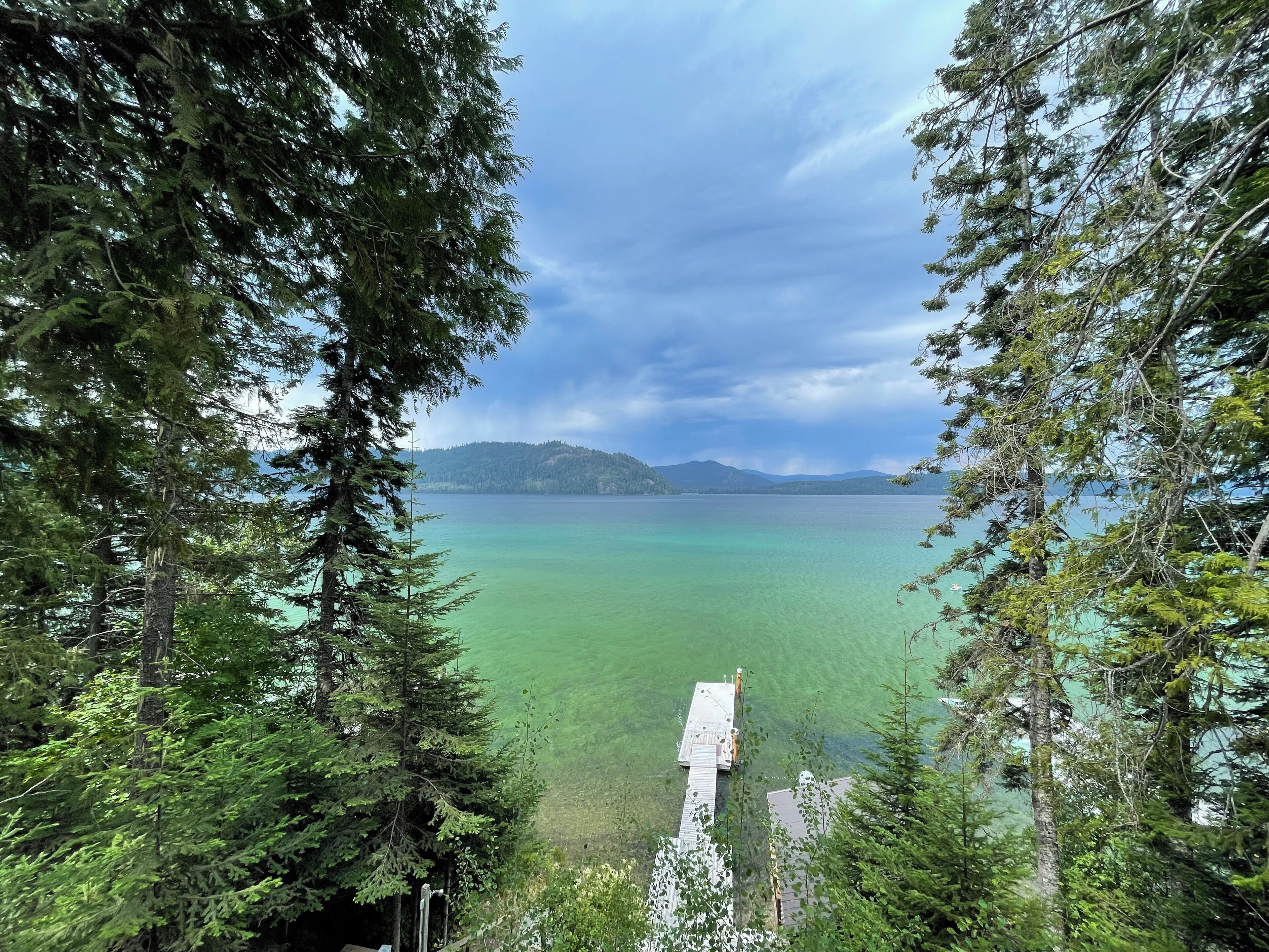 Une zone boisée avec une jetée qui s’avance sur un lac aux eaux claires, le tout étant entouré d’arbres.