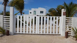 Une entrée fermée par un portail donnant accès à un immeuble à la façade blanche, avec une porte bien visible.