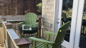 Eine Holzterrasse mit einem Glastisch und zwei Adirondack-Stühlen.