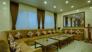 Una sala de estar con un sofá, dos mesas auxiliares y un espejo grande.
