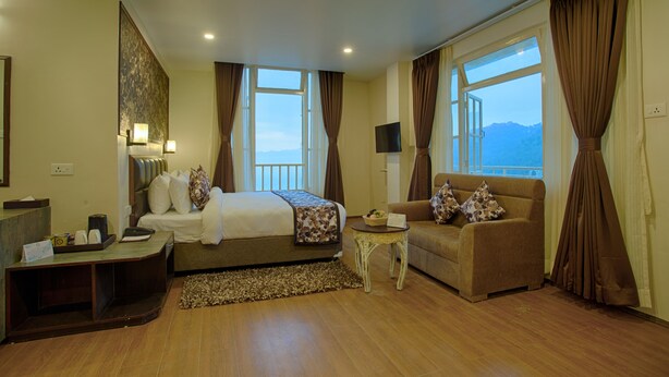 Una habitación de hotel con cama, sofá, mesita y televisor.