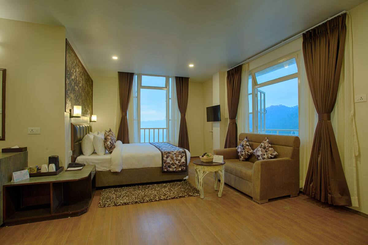 A hotel room with a bed, a sofa, a small table, and a TV.