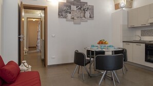 Een moderne keuken met een eethoek, met een centrale tafel met stoelen, een keukenblad en een hanglamp.