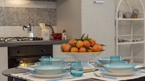 Een moderne keuken met een eettafel gedekt voor een maaltijd, met een fruitmand als decoratie en blauw servies.