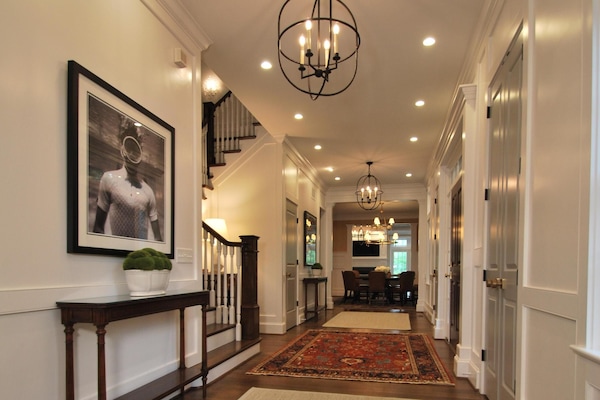 The home's 30+ foot entrance hall with black & white photography, white panelling and a concealed wet bar.