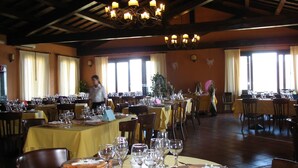 Un restaurant amb diverses taules preparades per dinar, amb lluminàries de cristall i grans finestres.