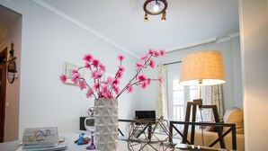 A living room with a white marble coffee table, a vase with pink flowers, a geometric candle holder, and a large floor lamp.