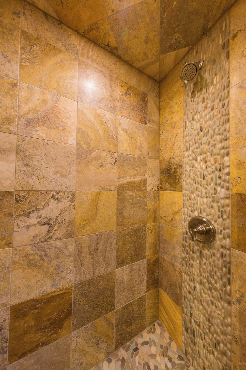 Une douche avec un mur en pierre et un sol carrelé.