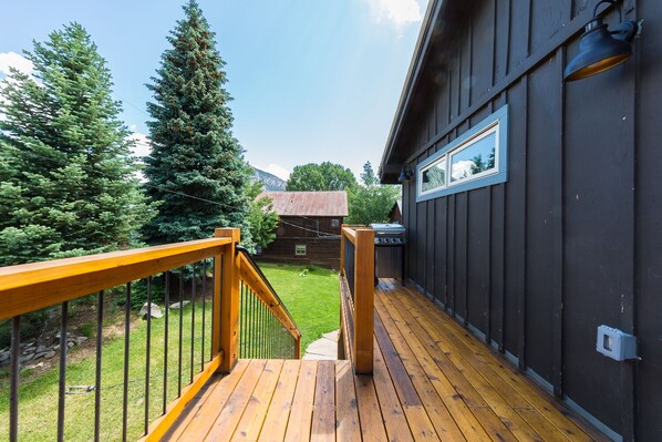 A wooden deck with a railing, a view of a mountain, and a rustic building in the background. - 3 Bedroom Apt in the Heart of Crested Butte! (Crested Butte)