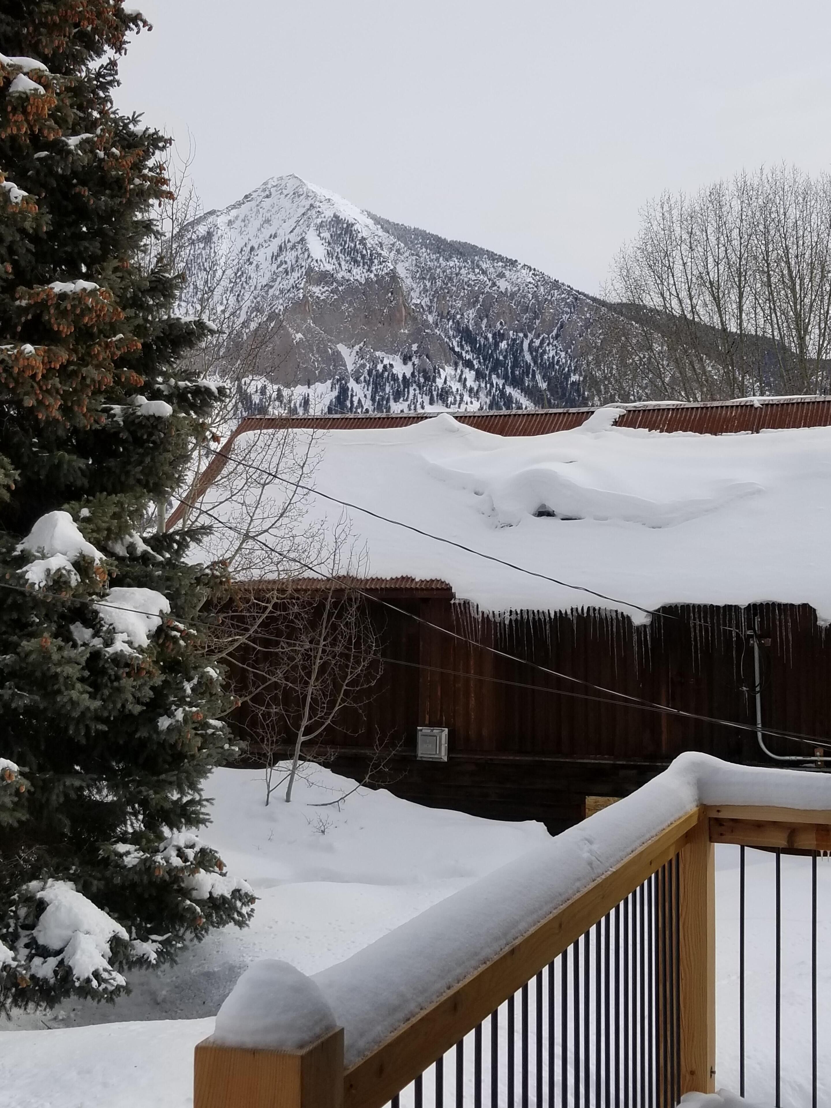 Un paisaje montañoso nevado con una valla de madera y una terraza cubierta de nieve.