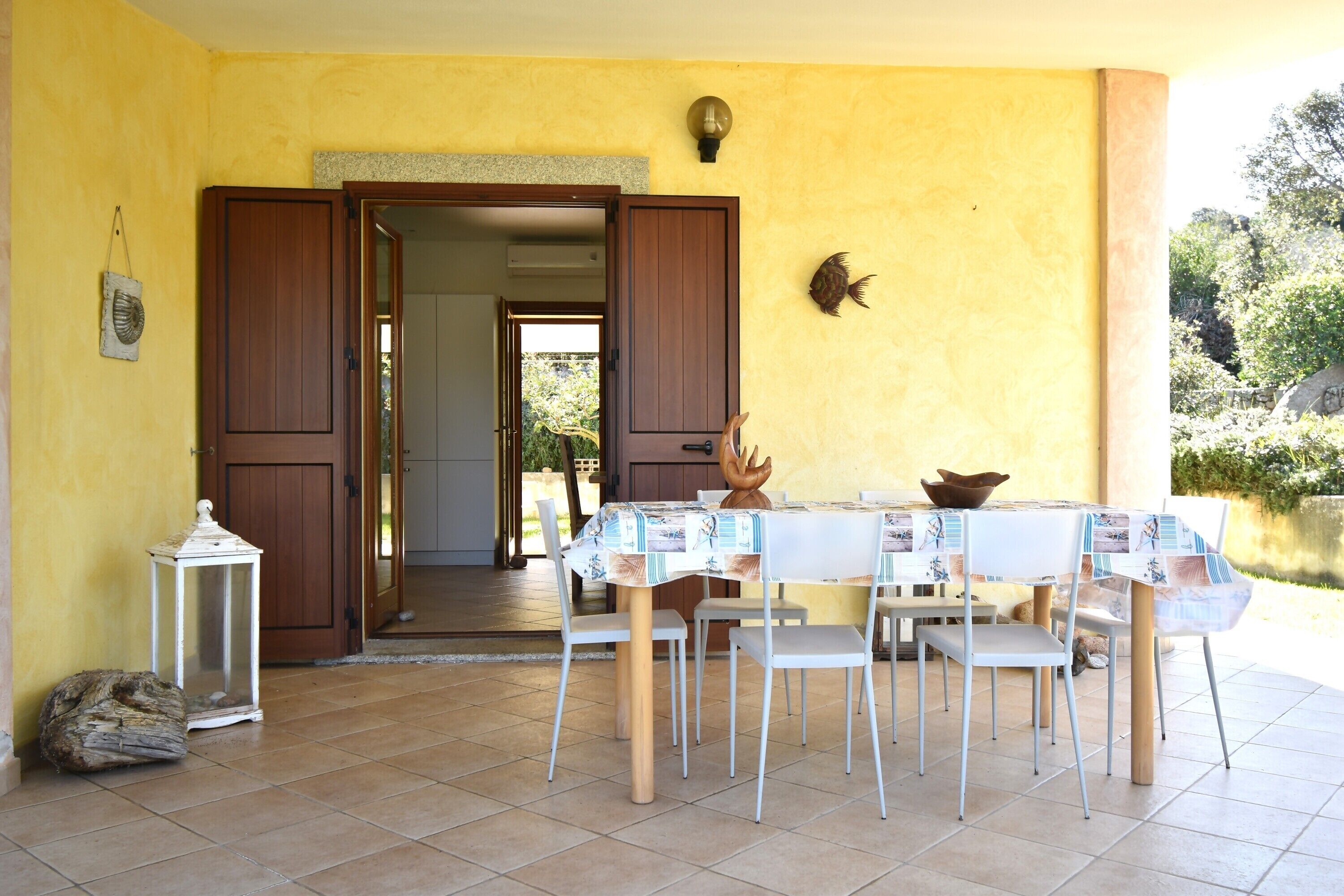 An open doorway leading to a room, a dining table with chairs, a lantern, and a decorative fish on the wall.
