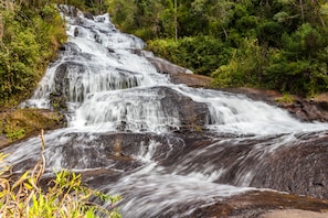 A waterfall cascading over rocks in a forested area. - Pousada Espelho DÁgua (Gonçalves)