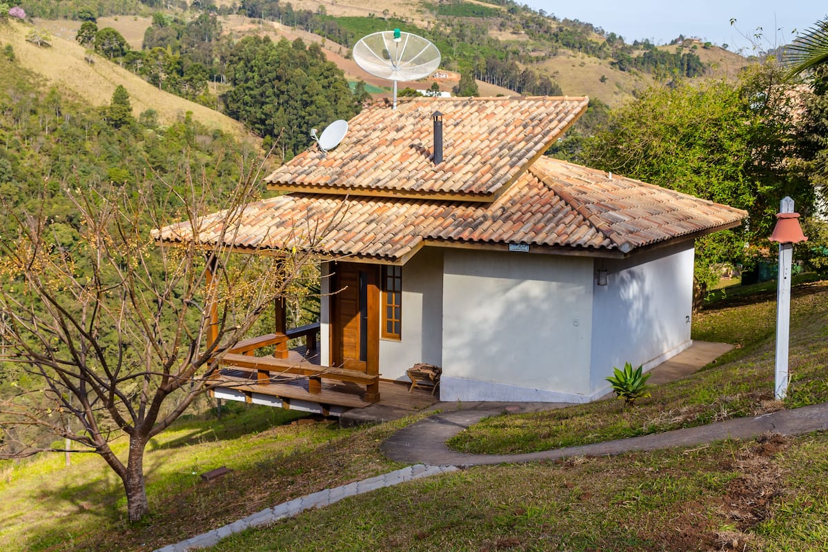 A small house with a tiled roof, a satellite dish, and a wooden deck.