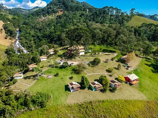 An aerial view of a rural village with several houses, a river, and a hill with a tower. - Pousada Espelho DÁgua (Gonçalves)
