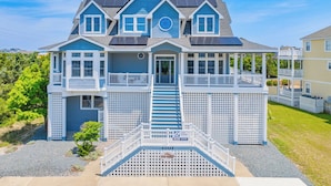 A two-story house with a front porch, a staircase leading to the entrance, and a small deck area. - Oceanview Home in Avon w/ Pool, Hot Tub, EV Charger, and Community Beach Access (Avon)