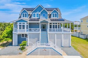 A two-story house with a front porch, a staircase leading to the entrance, and a small deck area.