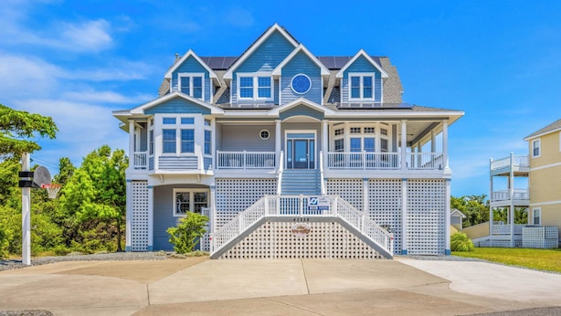 A two-story house with a front porch, a garage, and a small front yard. - Oceanview Home in Avon w/ Pool, Hot Tub, EV Charger, and Community Beach Access (Avon)