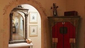 Un arco d'ingresso con uno specchio, quadri incorniciati e una porta rossa con una targa.