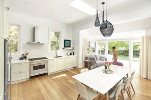 Una cocina moderna con armarios blancos, una isla grande y un comedor con mesa y sillas blancas.