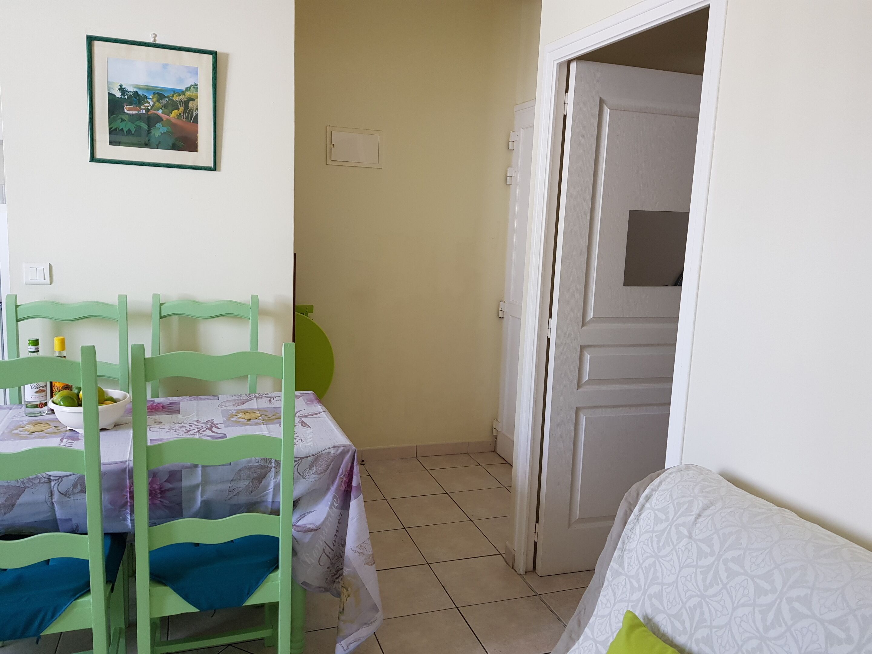 Um quarto com uma mesa de jantar e cadeiras, uma porta e uma parede com um quadro emoldurado.