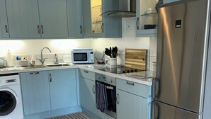 Cozinha moderna com armários azul claro, eletrodomésticos de aço inoxidável e micro-ondas embutido.