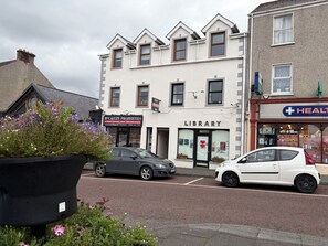 A street view with a library, a health store, and parked cars.