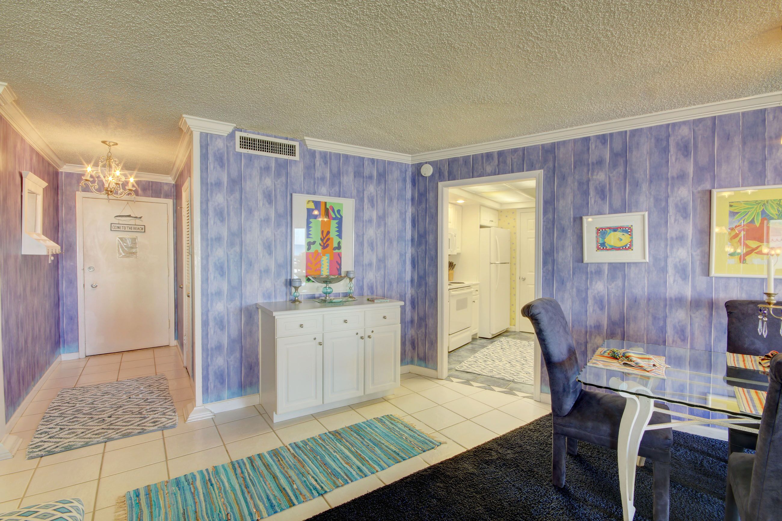 Ein modernes Interieur mit einer weißen Tür, einem blau-weißen Schrank, einem Glastisch und einem blauen Stuhl.