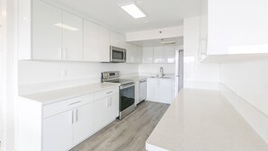 Una cocina moderna con armarios blancos, electrodomésticos de acero inoxidable y piso de madera clara.