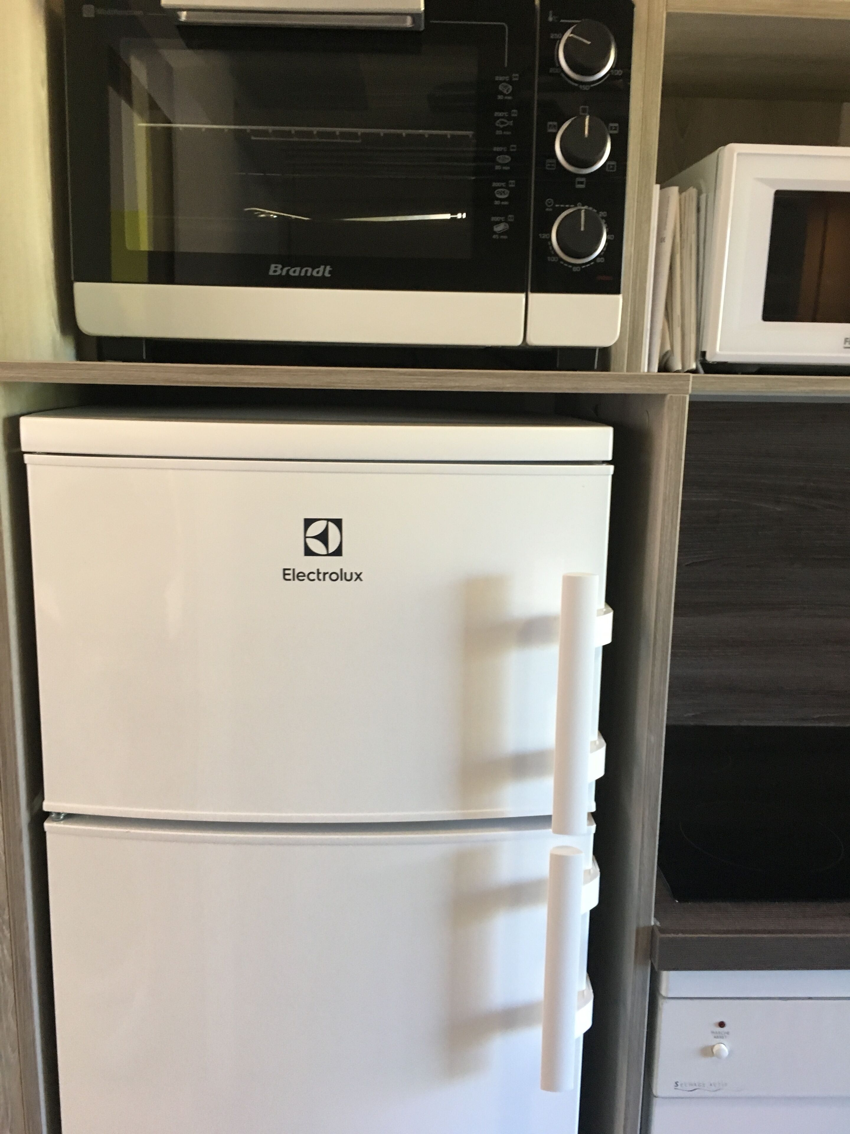 Une cuisine équipée d’un four à micro-ondes, d’un réfrigérateur et d’une cuisinière.