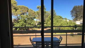 A balcony with a table and chairs, overlooking a dirt area with trees and a fence. - 2 rooms St Raphaël from Saturday 12/08 > 19/08/2023: €795 per week (Saint-Raphaël)
