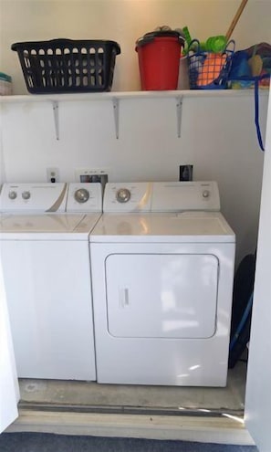 A laundry area with a washing machine and dryer, a basket, and a bucket.