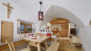 A cozy interior with wooden furniture, a cross on the wall, and a rustic stone floor.