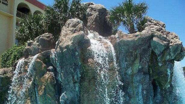 A pool with a rocky waterfall feature and a clear blue pool. - Destin West Villa 301, oceanview, wraparound balcony, lazy river, 6 pools, beach (Fort Walton Beach)