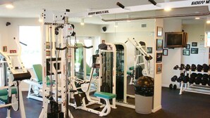 A gym with various exercise machines, a mirror, and a wall with framed pictures. - Destin West Villa 301, oceanview, wraparound balcony, lazy river, 6 pools, beach (Fort Walton Beach)
