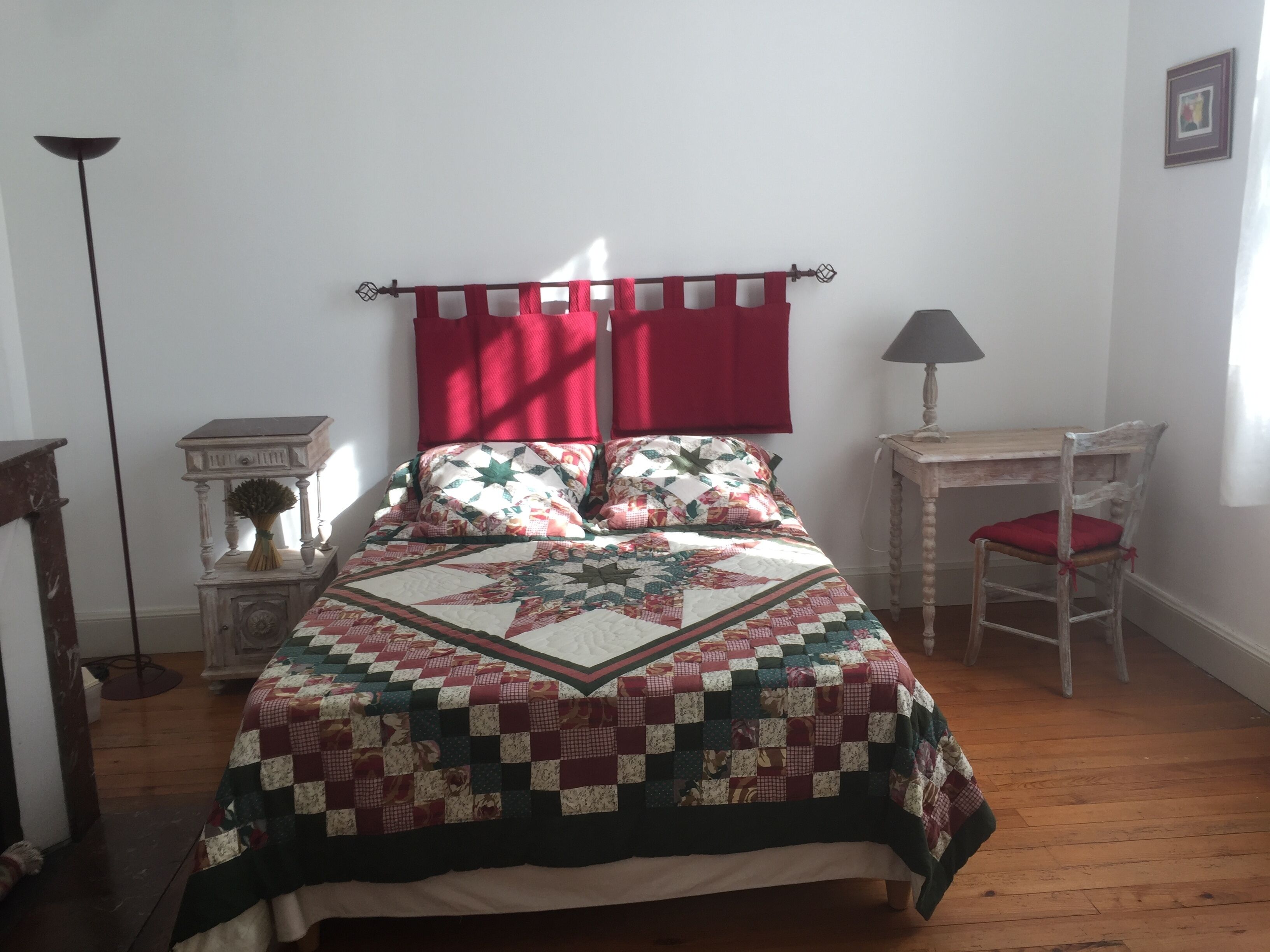 Quarto com uma cama grande, mesa de cabeceira, uma cadeira, abajur e um quadro na parede.