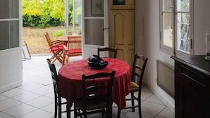 Een eethoek met een ronde tafel, stoelen, een klok en een kast.