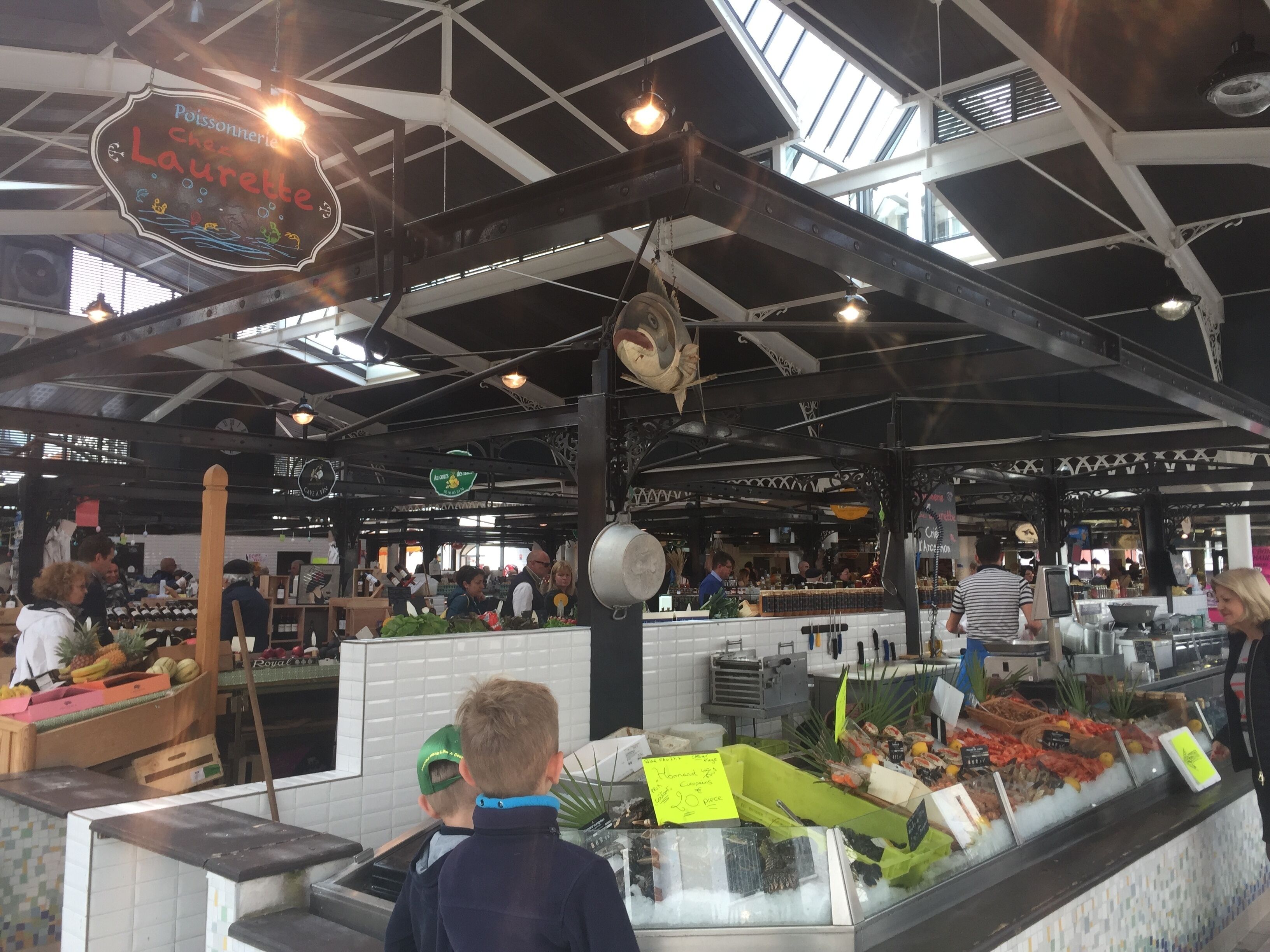 An indoor market with various food stalls and a ceiling with exposed beams and skylights.