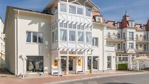 Ein zweistöckiges Gebäude mit Balkon, großen Fenstern und einer Schaufensterfront mit Dummys.