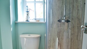 Un baño con inodoro, ducha y ventana con un adorno en el alféizar.