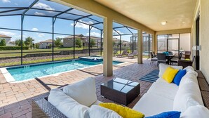 Ein überdachter Außenbereich mit Pool, Sitzgelegenheiten und Blick auf die Nachbarschaft.