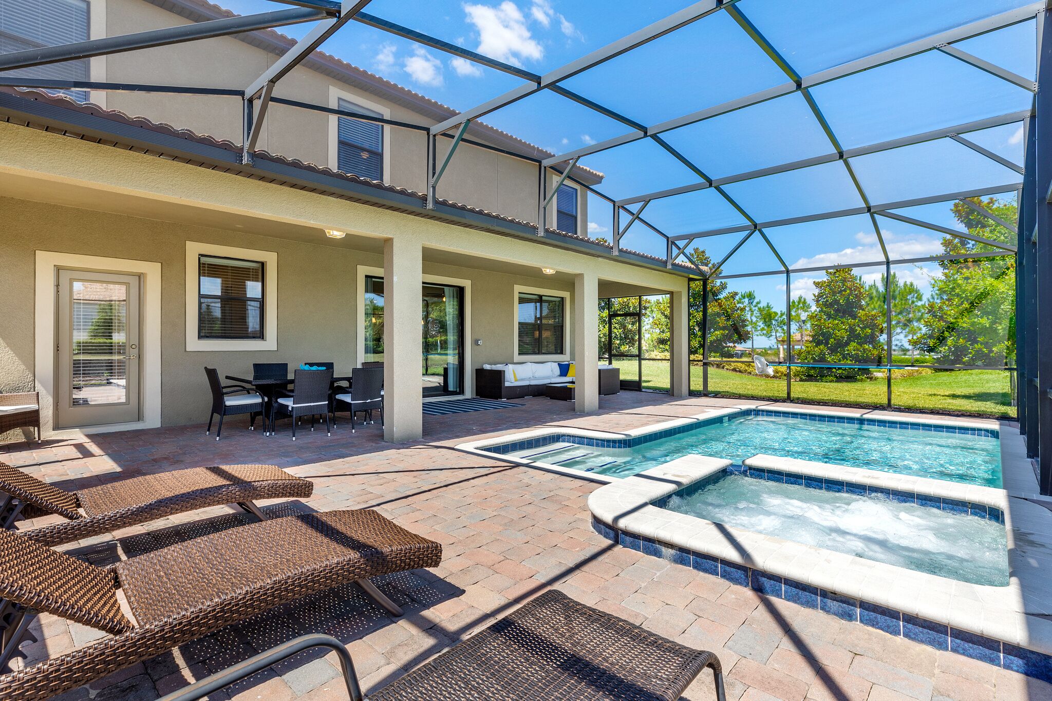 A covered patio with a pool, outdoor furniture, and a view of the surrounding landscape.