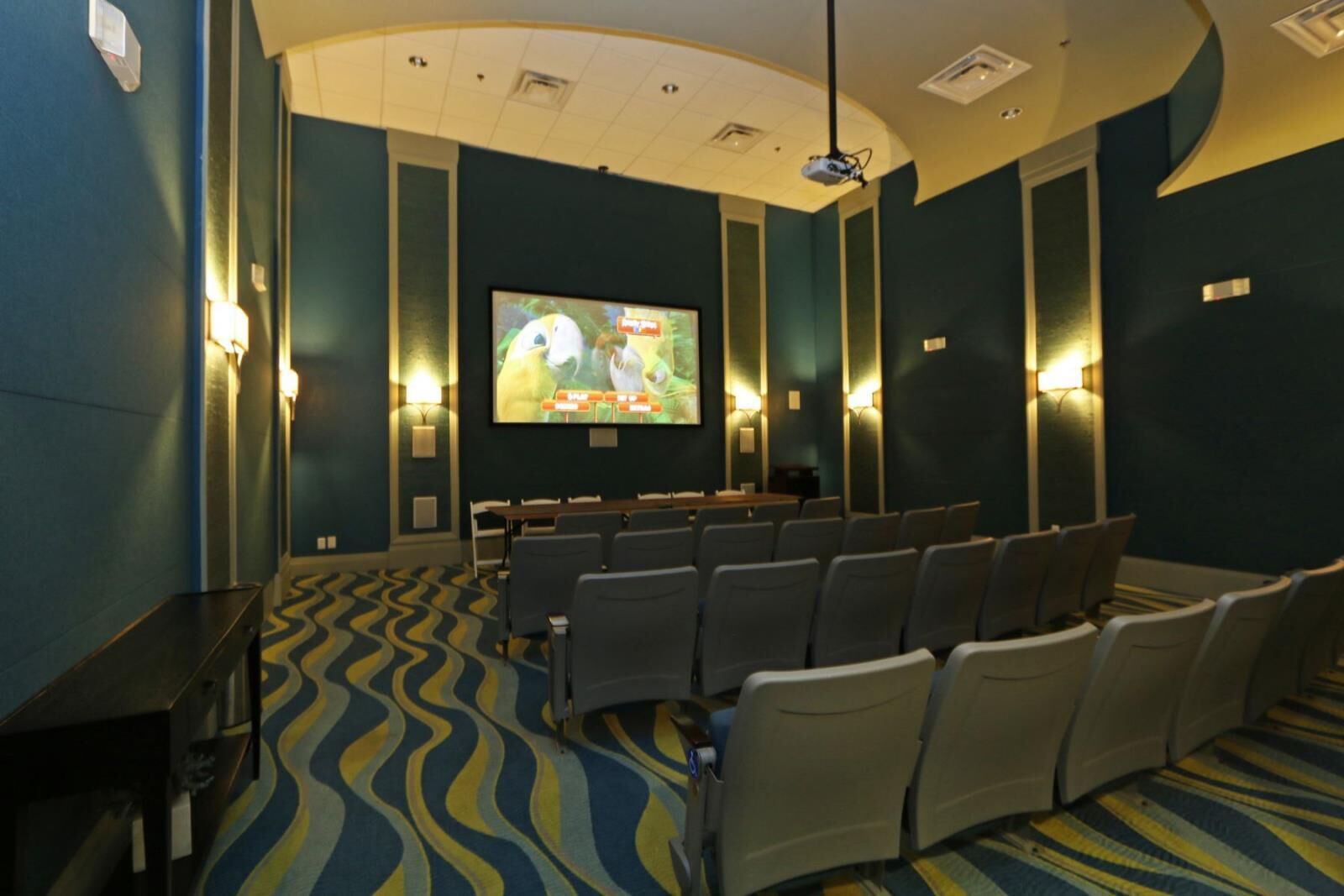 Un cinema amb files de seients, una pantalla gran i llums penjades a la paret.